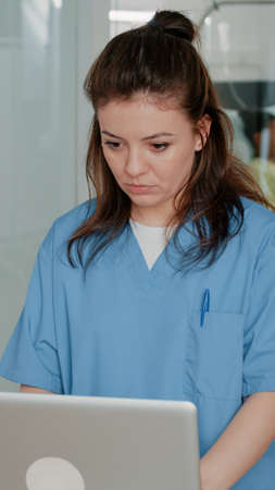 Medical assistant working with computer to help doctor with healthcare information. Woman nurse using monitor to find treatment for patient in hospital ward. Specialist browsing internetの写真素材