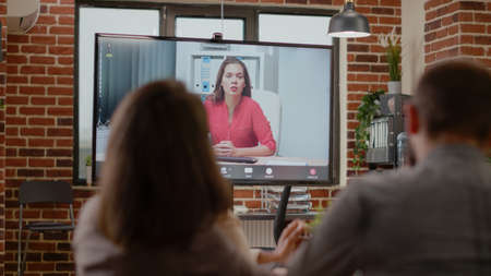 Close up of workmates talking on online video call with woman, using remote video teleconference for communication with colleagues. Video conference telecommunication on displayの写真素材