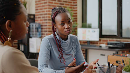 Close up of business woman presenting project ideas with group of people at office meeting. Employee working with colleagues on marketing presentation and strategy for development.の写真素材