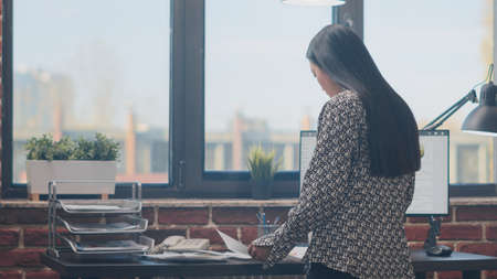 Close up of employee working with documents and computer to plan business project in office. Woman...
