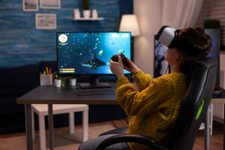 Gamer woman wearing virtual reality headset while playing space shooter video games for online competition on computer usimg gaming joystick. Streamer player doing entertainment activitiesの写真素材
