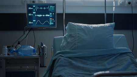 Empty hospital ward prepared for patient healthcare at modern medical facility. Nobody in intensive care room equipped with reanimation technology, monitor, surgery equipment and bedの写真素材