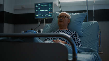 Sick elderly man with health problems staying in hospital ward bed prepared for medical treatment....