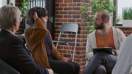 Close up of nervous woman with alcohol addiction having mental breakdown at aa meeting. Person having desperate reaction in front of people and psychologist at therapy session.の写真素材