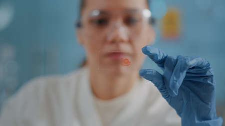 Woman biologist analyzing blood sample on glass tray to find diagnosis in laboratory. Researcher...