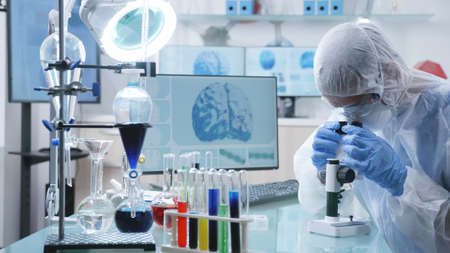 Chemist researcher doctor with ppe equipment analyzing dna sample using microscope during medical...