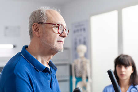 Close up of aged patient using gear for physical exercise and recovery after accident. Man with...