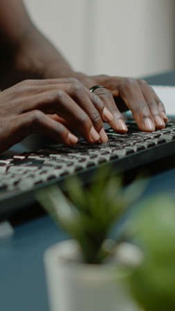 Close up of hands using computer keyboard and listening to music for business remote work. Man dancing and singing while working from home with technology. Worker having fun at deskの写真素材