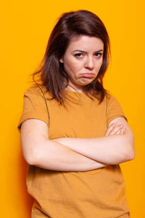Annoyed woman posing with crossed arms on camera, showing disapproving and displeased facial...