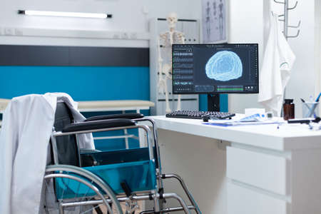 Modern empty hospital office having computer with brain radiography on screen ready for oncology examination. Cabinet room equipped with medical professional tools. Brain tomography imageの写真素材