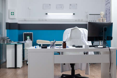 Empty medical office equipped with modern furniture ready for clinical examination. Hospital workplace with nobody in it having disease documents on table. Medicine servicesの写真素材