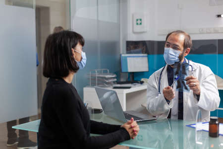 Specialist and patient looking at radiography scan in office. General practitioner explaining x ray...