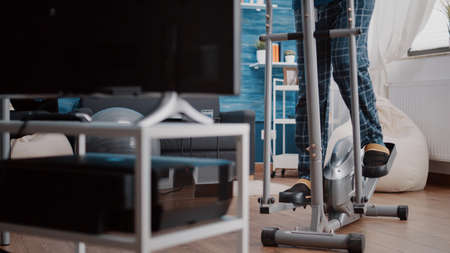 Senior man training with cardio stationary bicycle. Aged person using fitness equipment to do...