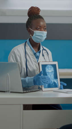 Young medic showing modern tablet with x ray scan to senior ill man at healthcare facility with...