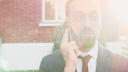 Portrait of businessman talking at smartphone discussing strategy problem with remote entrepreneur. Executive manager solving disagreement ouside in front of business office building. Outdoors conceptの写真素材