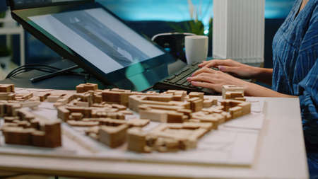 Close up of building model on table and woman using touch screen, analyzing maquette on computer....