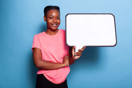 Portrait of cheerful african american teenager smiling at camera while holding empty text banner...