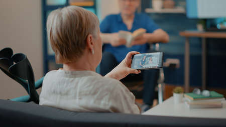 Old woman using smartphone to talk to family in hospital on videocall. Senior person talking to...