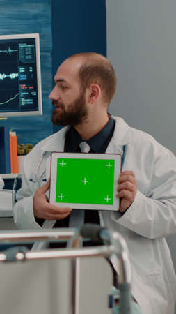 Doctor with horizontal green screen on tablet talking to patient in nursing home. Senior woman with...