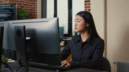 Portrait of asian programer focused on writing code sitting at desk in software development office. System engineer concentrating on creating algorithm for it startup company.の写真素材