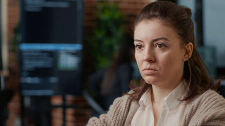 Portrait of caucasian software developer working focused looking at computer screen while typing in it startup office. System engineer writing code with colleagues online cloud computing.の写真素材
