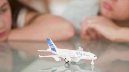 Closeup of mother and daughter looking at toy plane dreaming at nature holiday during coronavirus quarantine. Family imaginating dream adventure. Concept of outdoor vacations. Summer vacationの写真素材
