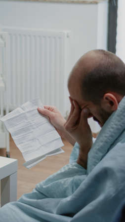 Adult with migraine reading paper with information about medication against flu symptoms. Sick man...