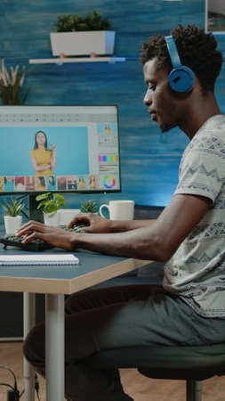 Photography editor with headphones working with retouch app to edit pictures. Photographer doing retouching work on computer for studio production. Graphic designer editing photoの写真素材