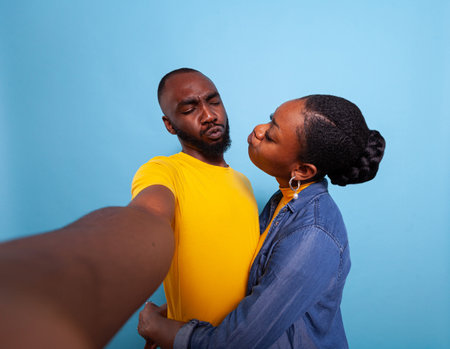 People in love doing kissy face at each other and taking pictures on camera. Joyful boyfriend and girlfriend enjoying sweet moment, expressing romantic feelings and love. Partners hugging.の写真素材