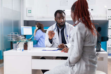 Pregnant woman at checkup appointment with physician in medical office. Patient with pregnancy discussing with general practitioner about healthcare and parenthood at consultationの写真素材