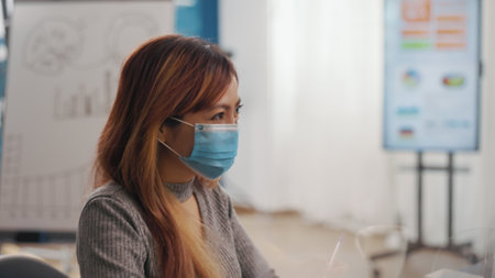 Job candidate attending meeting with human resources employee, wearing face mask. Asian woman having interview appointment with consultant, talking about hiring and recruitment during pandemicの写真素材