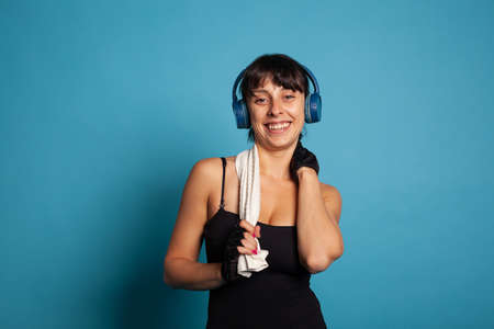 Smiling active trainer wearing headphones listening music while training body muscles during pilates...