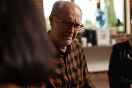 Close up of old man sharing anxiety problems with group at therapy session. AA meeting person...