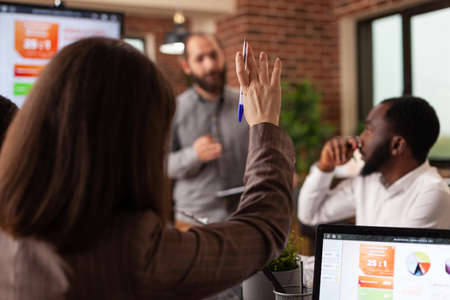 Businesswoman having rising hand having marketing question during business meeting working at...