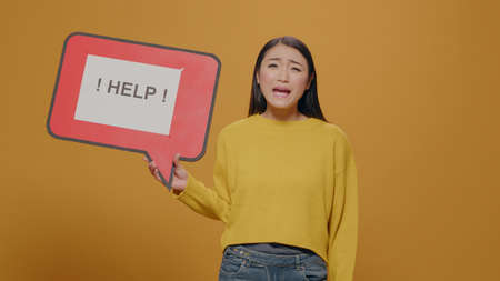Woman holding speech bubble with text message, asking for help in studio. Desperate person showing...