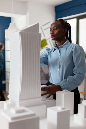 Portrait of architect looking at the architecture design of futuristic building at desk with...