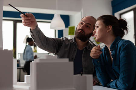 Architectural designers team pointing pen at skyscraper discussing architecture design in modern...