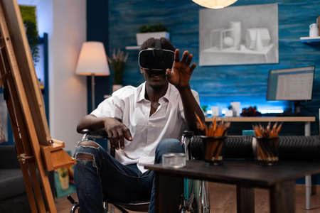Young artist with virtual reality goggles imagining draw illustration while working at art...