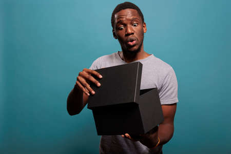 Excited person feeling surprised after unpacking gift box and opening to see delivery order. Shocked man unboxing package present from postal delivery service, enjoying shopping surprise.の写真素材