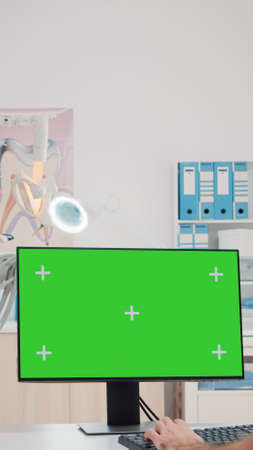 Dental assistant using monitor with horizontal green screen in dentist office. Oral care specialists working with teethcare equipment and chroma key for isolated background in cabinet.の写真素材