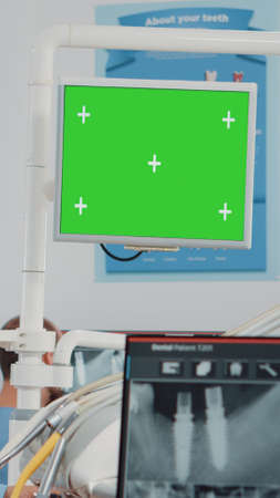 Woman working as dentist with green screen and x ray scan for teethcare in dental cabinet. Oral care specialist analyzing chroma key with isolated mockup template and teeth radiographyの写真素材