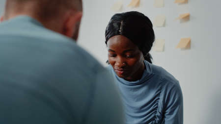 Close up of african american woman playing soccer game with man at foosball table after work. Workmates having fun with play, enjoying free time at office. Colleagues enjoying activityの写真素材