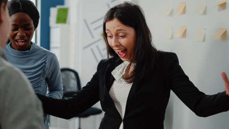 Close up of happy woman winning game at foosball table, playing with office coworkers after work. Person enjoying free time and drinks to do fun activity with colleagues after hours.の写真素材