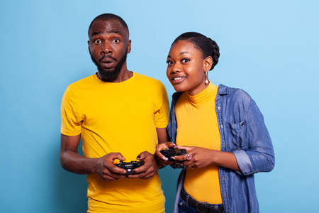 Man and woman using jpystick to play video games in studio, having fun in relationship. Happy couple...