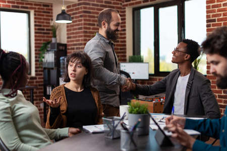 Businessman shaking hand with manager during business meeting in startup office. Multi-ethnic businesspeople discussing company turnover working at marketing strategy brainstorming ideasの写真素材