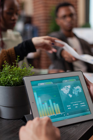 Closeup of entrepreneur holding tablet computer with marketing statistics on screen. Multiethnic...