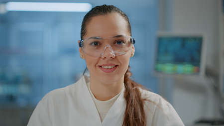 Portrait of woman scientist with goggles smiling in laboratory, getting ready to work on science experiment and development. Microbiology researcher wearing safety glasses in lab. Close upの写真素材