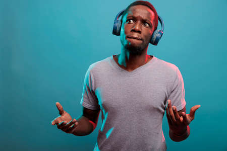 Man with thoughtful expression listening to music on headphones, having fun with modern audio sound....