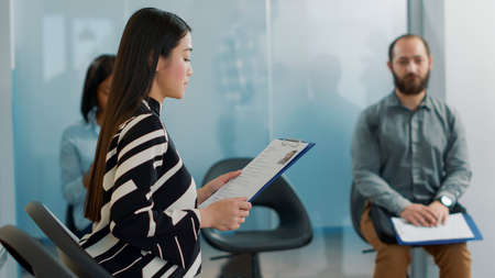 Pregnant worker inviting female applicant to attend job interview with HR team in company office. Candidate and employee joining employment meeting, having cv information files.の写真素材