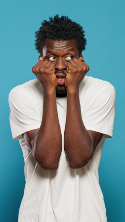 Portrait of frightened man having hands on mouth. Scared person feeling anxious and panicked in...